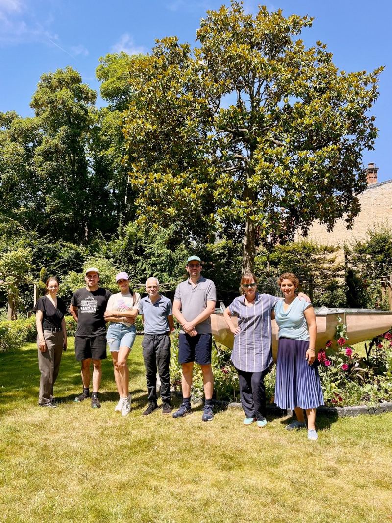 Somayeh avec une équipe de bénévoles dans un jardin, debout devant un grand magnolia