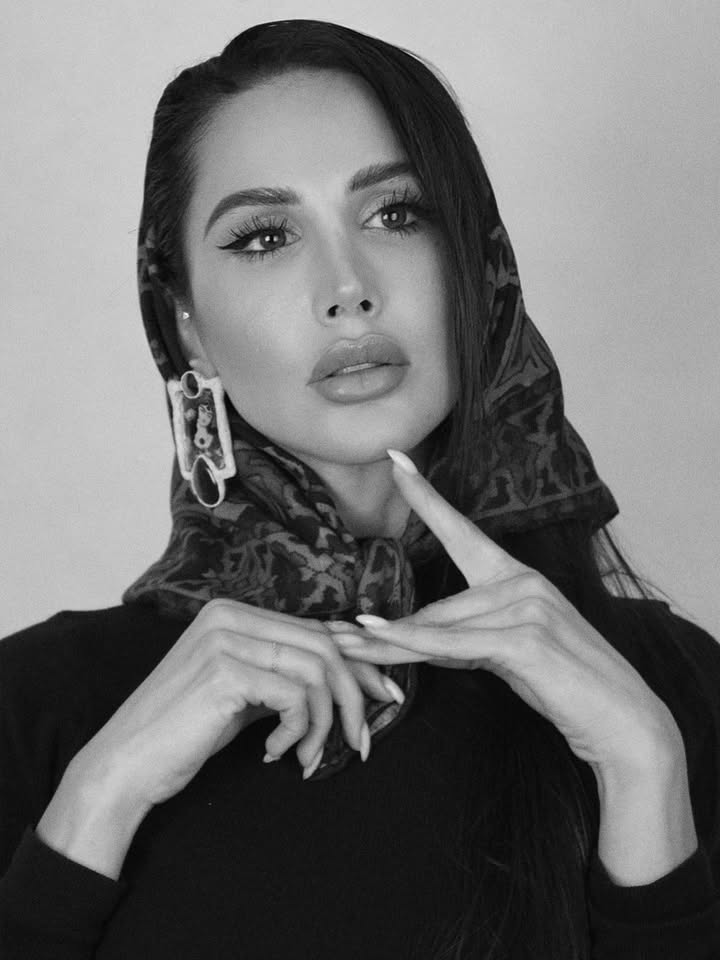 Portrait en noir et blanc de Somayeh, les cheveux couverts d’un foulard à motifs, les mains croisées sous le menton